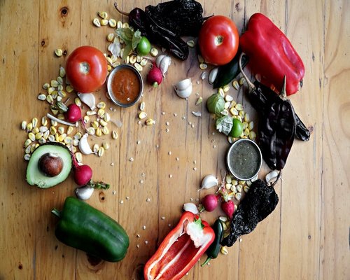A variety of fresh Mexican ingredients like tomatoes, avocados, and beans on a rustic table