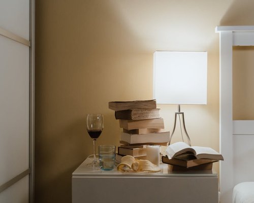 A glass of water next to a book on a bedside table in soft morning light